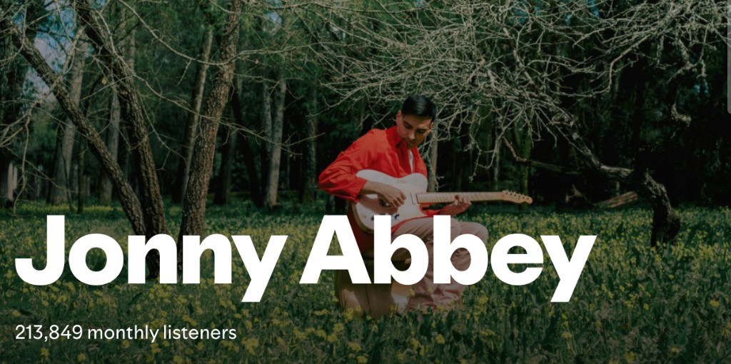 Jonny Abbey Spotify artist profile: seated with a white electric guitar in a wooded area, with 213,849 monthly listeners shown